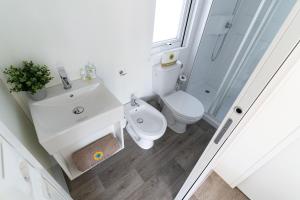 a white bathroom with a toilet and a sink at Club del Sole Rimini Family Resort in Rimini