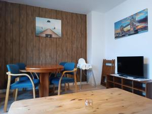 a dining room with a table and blue chairs and a television at Südkiez62 in Wilhelmshaven