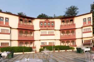 un edificio con mesas y sillas delante de él en Treebo Trend Hotel Kumbhal Castle 2 Km From Kumbalgarh Fort, en Kumbhalgarh