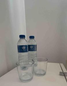two bottles of water and two glasses on a table at Apartamento Santiagos Road in O Pedrouzo