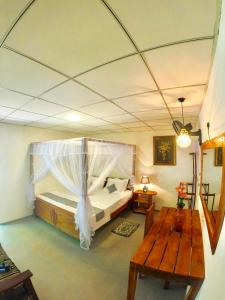 una camera con un grande letto e un tavolo in legno di Ostello Surf Resort ad Ahangama