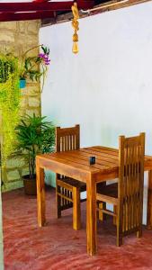 a wooden table and two chairs and a table and a plant at Ostello Surf Resort in Ahangama