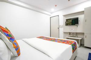 een witte kamer met een bed en een televisie bij FabHotel Grey Sky in Gandhinagar