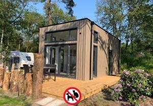 a small wooden house with a sign in front of it at Tiny House in Baarle-Nassau