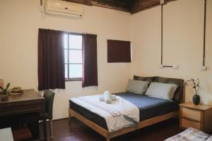 a bedroom with a bed and a desk and a window at A Touch of Zen in Kaohsiung