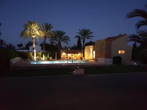 une maison avec des palmiers et une piscine la nuit dans l'établissement El Campirri, à Daimés