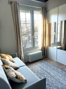 - un salon avec un canapé et une grande fenêtre dans l'établissement Chambre avec mezzanine dans une maison d'artiste, à Rueil-Malmaison