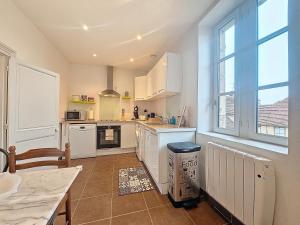 a kitchen with white appliances and a large window at Le Régemortes, centre ville et proche du CNCS, avec services premium by PRIMO C0NCIERGERIE in Moulins