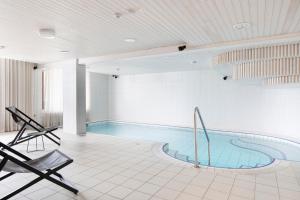 a swimming pool in a building with two chairs at Original Sokos Hotel Tapiola Garden Espoo in Espoo +24 photos