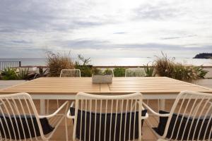 a wooden table and chairs with a table and the ocean at CASA SOL I PLATJA Calella Palafrugell con Parking in Calella de Palafrugell