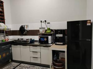 Firdzura Home Semi D في كُوانتان: مطبخ مع ثلاجة سوداء وميكرويف