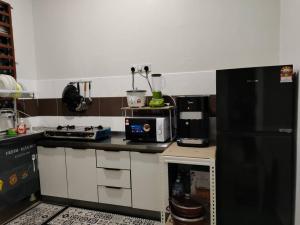 uma cozinha com um frigorífico preto e um micro-ondas em Firdzura Home Semi D em Kuantan