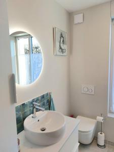 La salle de bains est pourvue d'un lavabo, de toilettes et d'un miroir. dans l'établissement Chambre avec mezzanine dans une maison d'artiste, à Rueil-Malmaison