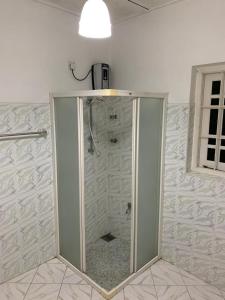 La salle de bains est pourvue d'une douche avec une porte en verre. dans l'établissement Mohotti House, à Galle