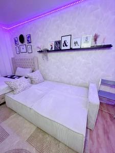 a bedroom with a white bed and a purple lighting at Appartement proche stade de France et métro 12 in Saint-Denis