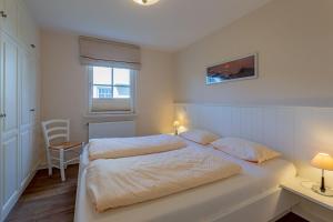een slaapkamer met een groot wit bed met 2 kussens bij Bonsum EG R in Wyk auf Föhr