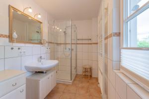 een witte badkamer met een wastafel en een douche bij Bonsum EG R in Wyk auf Föhr