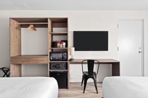 a bedroom with a desk with a tv and a chair at Developer Inn Highway, A Howard Johnson by Wyndham in Kissimmee