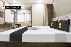 a bedroom with a large white bed with black pillows at Super Townhouse Vashi Sector 28 in Turambhe