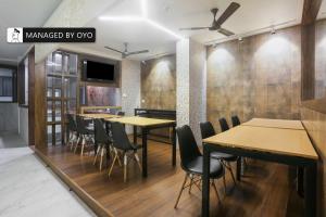 a dining room with wooden tables and chairs at Super Townhouse Vashi Sector 28 in Turambhe