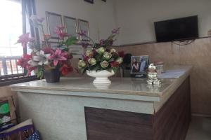 a counter with flowers in a vase on it at Hotel Orchid Syariah in Tegal