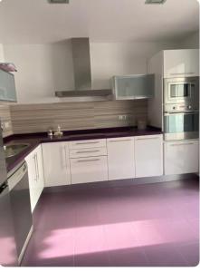 cocina con armarios blancos y suelo rosa en Apartamento Patty, en Elche