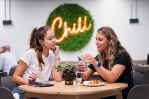 dos chicas sentadas en una mesa comiendo comida en Habitat Aparthotel by Totalstay, en Ciudad del Cabo