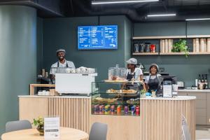 three people standing at a counter in a coffee shop at Habitat Aparthotel by Totalstay in Cape Town