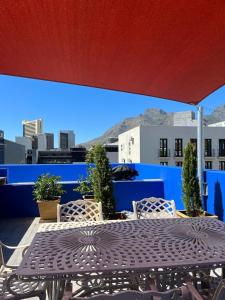 een tafel en stoelen onder een parasol op een dak bij Modern city townhouse with rooftop terrace in Kaapstad