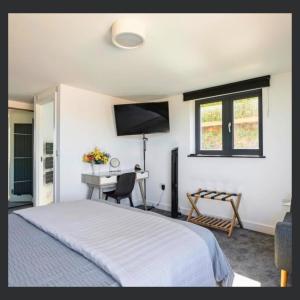 a bedroom with a bed and a desk with a television at Uno St Ives - Luxury Serviced Accommodation in St Ives