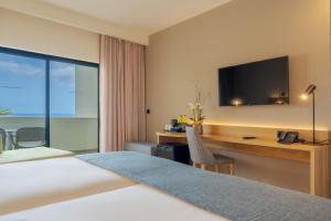 カニコにあるSentido Galosolのベッド、デスク、テレビが備わるホテルルームです。