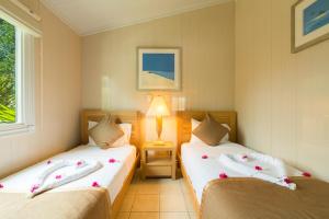 Turtle Cove的住宿－Kokomo Botanical Resort - Caribbean Family Cottages，一间卧室配有两张鲜花床。