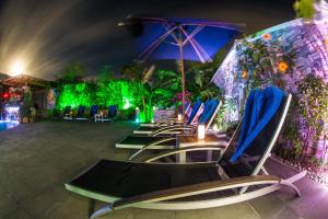 a row of lounge chairs with an umbrella and lights at Kokomo Botanical Resort - Caribbean Family Cottages in Turtle Cove