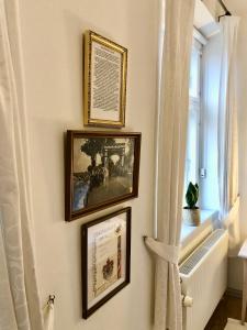 3 gerahmte Bilder an einer Wand mit Fenster in der Unterkunft Brødremenighedens Hotel in Christiansfeld