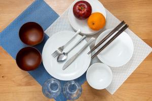 une table avec des assiettes et des ustensiles, une pomme et des oranges dans l'établissement Voga Kolte Chidorimachi - Vacation STAY 2163, à Tokyo