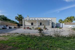 a white house with a fence and palm trees at Villa Torre Guaceto by Typney in Carovigno