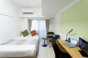 Habitación de hotel con cama y escritorio con ordenador portátil en Voga Kolte Chidorimachi - Vacation STAY 7883, en Tokio