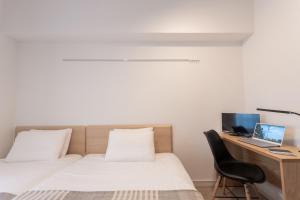1 dormitorio con 1 cama y escritorio con ordenador portátil en Voga Kolte Chidorimachi - Vacation STAY 7883, en Tokio