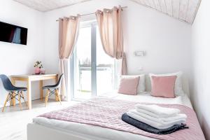een witte slaapkamer met roze gordijnen en een bed bij Willa Alexandria - Domki, Apartamenty, Pokoje z Basenem in Karwia