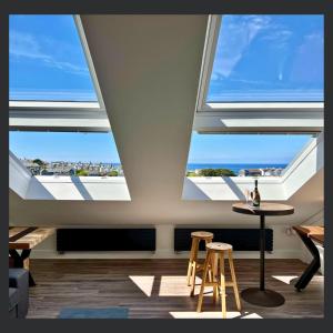 a room with three large windows with a table and stools at Uno St Ives - Luxury Serviced Accommodation in St Ives