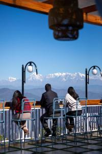 un gruppo di persone sedute a un tavolo che guardano le montagne di Kasar Himalaya Holiday Home, Binsar Rd ad Almora