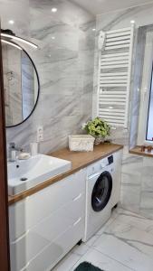 a bathroom with a washing machine and a sink at Apartament Renii in Tomaszów Mazowiecki
