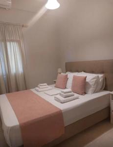 1 dormitorio con 1 cama grande con almohadas rosas y blancas en Odyssey's Feats, en Plati