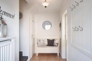 a white hallway with a white chair and a mirror at Haus Amrumblick in Hedehusum
