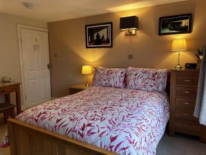 a bedroom with a bed with a red and white comforter at The Old Posthouse B&B in Caenby