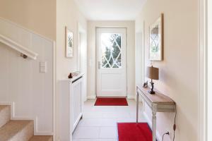 a hallway with a white door and a red rug at Haus Auswanderer 2 in Nieblum