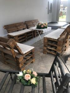 um quarto com cadeiras e mesas de madeira e flores em Guest House Anna Vendégház em Svetozar Miletić