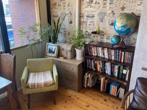 a room with a book shelf with books and a chair at Nawate Guesthouse in Matsumoto