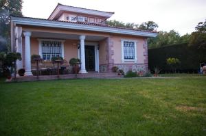 una casa rosa con césped delante en Casa Rural El Camino de Yuste, en Cuacos de Yuste