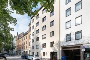 a tall white building with cars parked in front of it at MARIENPLATZ Apartment 2 bedrooms living room kitchen in Munich